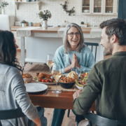 Modern multi-generation family communicating and smiling while having Thanksgiving dinner together
