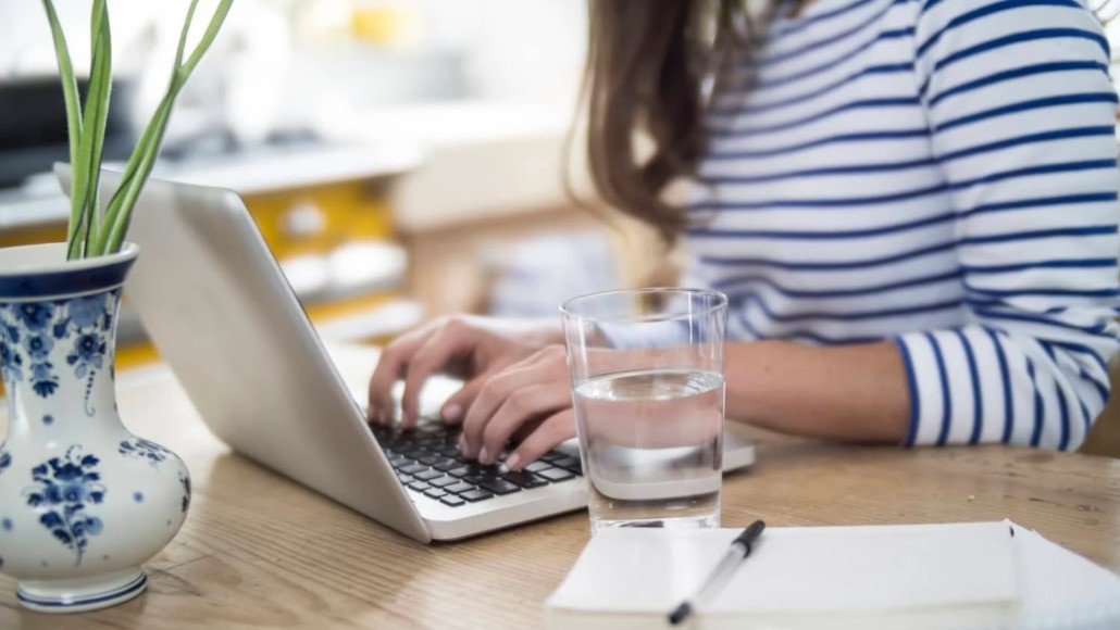 Woman working at desk with a glass of water next to her