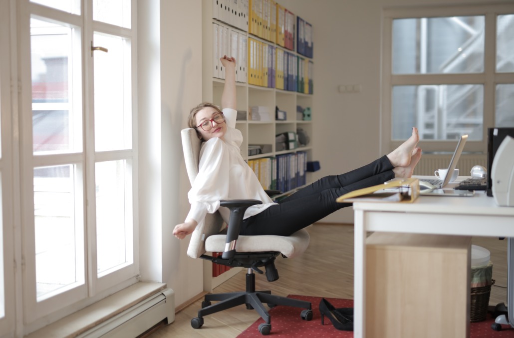 Woman stretching at her home desk demonstrates being resilient and productive at work at home